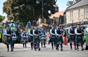 Scottish pipe band in traditional dress processing along Aberlady High Street